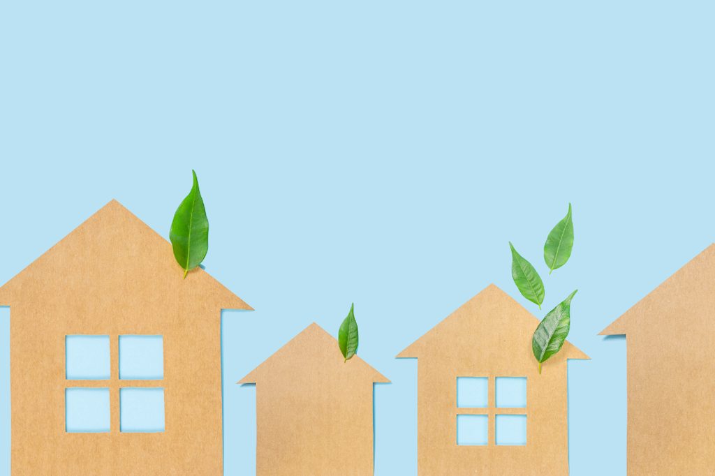 maisons en carton avec des feuilles vertes, symbolisant des hebergements ecoresponsables